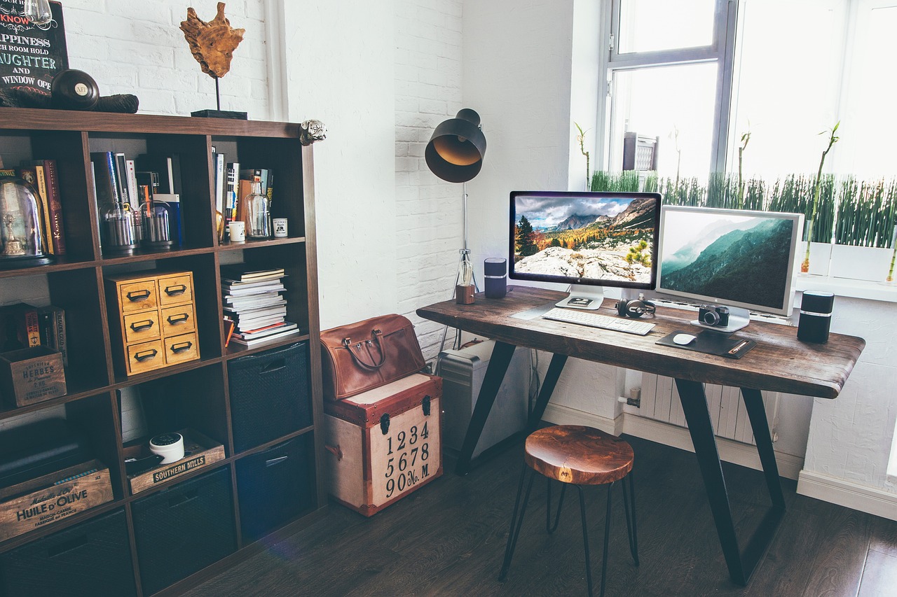 Alt Text: A professional and clean trading desk setup featuring a dual-monitor workstation on a wooden desk, a comfortable mesh chair, and an organized home office background.