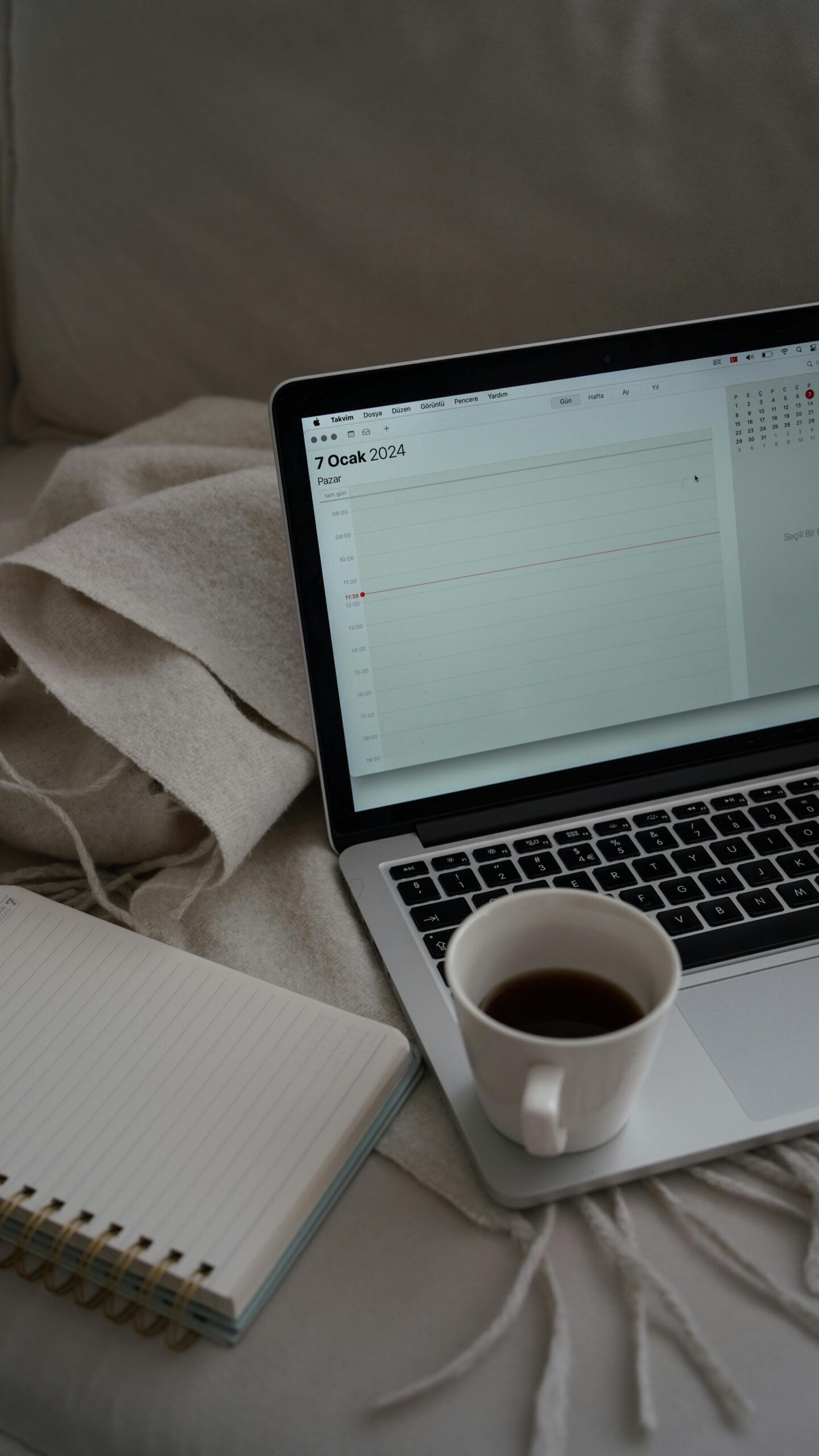 A cozy workspace features a laptop, notebook, and coffee cup on a comfy setup in Ankara, Türkiye.